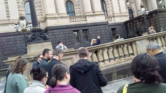 Księża modlący się z wiernymi przed budynkiem Parlamentu Wiktorii